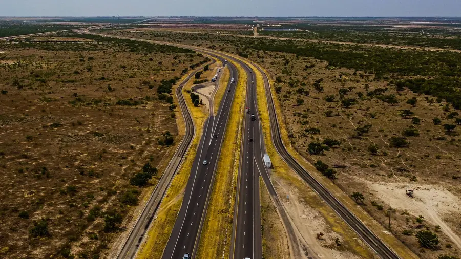 Highway running through flat, dry West Texas brush country